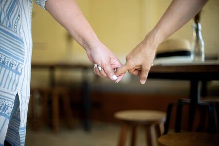 Woman and her friend hand together finger to hand, friend hook each other's little finger, walking togetherの写真素材