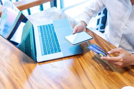 Young woman use credit card near the computer laptop and smartphone, on the wood desk table.の写真素材