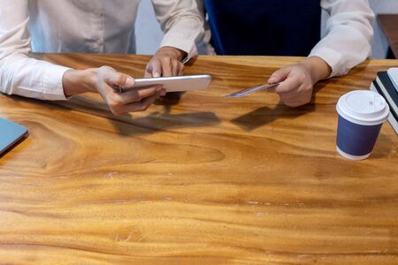 Young woman use credit card near the computer laptop and smartphone, on the wood desk table.の写真素材