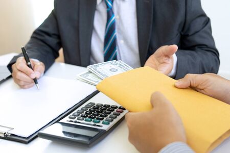 Business man give bribe to the officer under contact paper, concept corruption moneyの写真素材