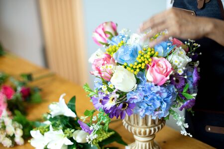 florist store flower artist woman working to decorate  artificial flowers decorate on the table with many  color of paper and plastic flowerの写真素材