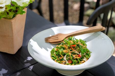 Asian food on the white dish with wood spoon, outdoor on the tableの写真素材