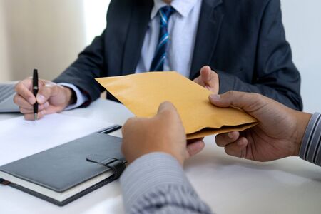 Business man give bribe to the officer under contact paper, concept corruption moneyの写真素材