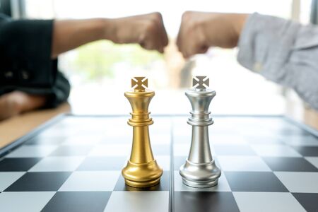 On the chess board, Businessman fist bump  near  silver  king and gold king chess color on the office desk.の写真素材