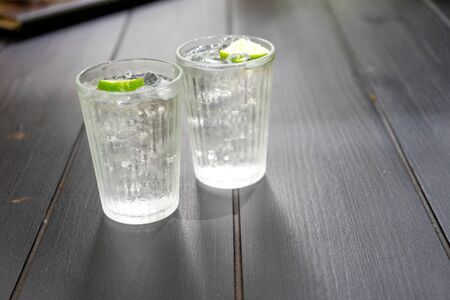 glass of cold water with lemon slide on the black wood water.の写真素材