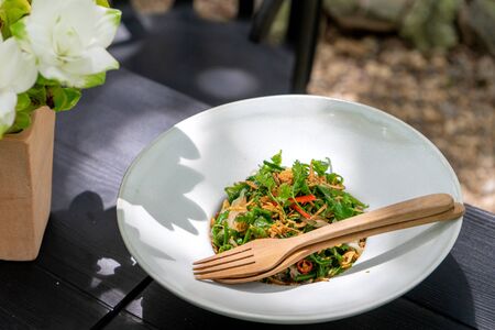 Asian food on the white dish with wood spoon, outdoor on the tableの写真素材