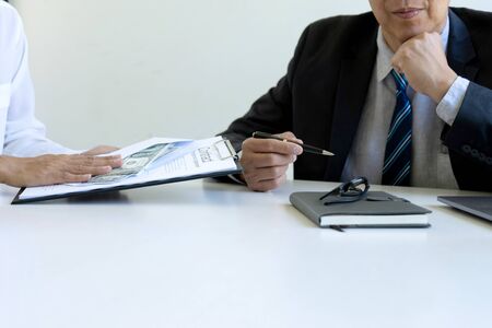 Business man give bribe to the officer under contact paper, concept corruption moneyの写真素材