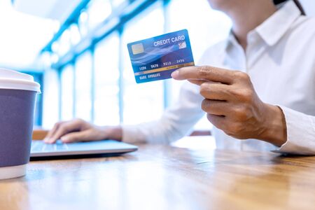 Young woman use credit card near the computer laptop and smartphone, on the wood desk table.の写真素材