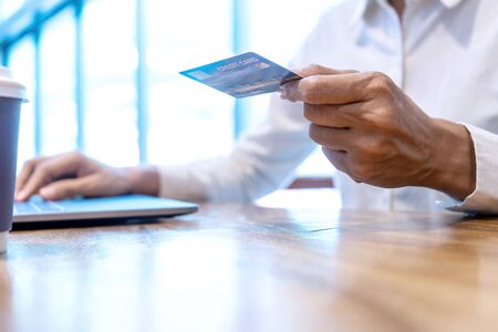 Young woman use credit card near the computer laptop and smartphone, on the wood desk table.の写真素材