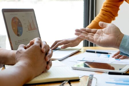 staff hand point to laptop, Young businessman creative meeting in the office working with graph and chart on the tableの写真素材