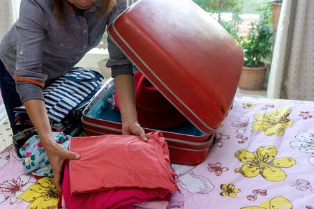 A woman packing the luggage prepare for her journey trip with a lot of her cloth,の写真素材