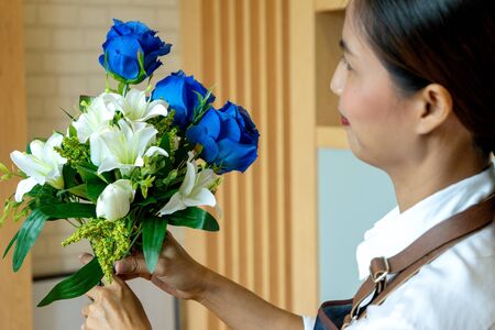 image of flower artist woman working to decorate  artificial flowers decorate on the table with many  color of paper and plastic flowerの写真素材