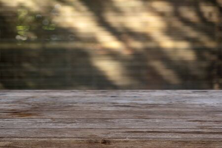 Empty wooden table with blurred background light and shadow in brown dark toneの写真素材