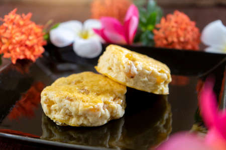 Two Scone are on the black dish with nature With colorful flowers in the backgroundの写真素材