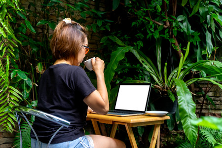 Businesswoman Working on the desk in the green garden at home, concept office work at home away from cover 19 or quarantined. with  white computer  screen computer screen with  clipping pathの写真素材