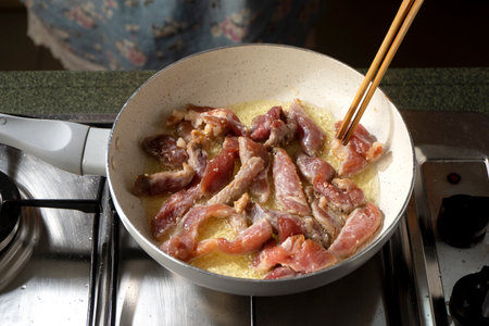Dried Pork slices are frying on the pan with oil.の写真素材
