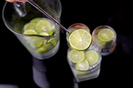 Focus to Slice lemon on the spoon with glass jug in the dark tone black backgroundの写真素材