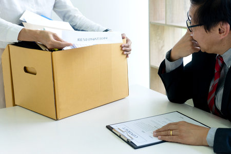 Staff worker hold the box and send resignation letter to boss or manager to tell that she quite from the jobの写真素材