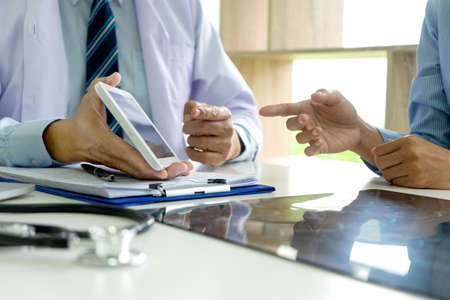 The doctor used a tablet to explain the symptoms and treatment methods to the patient and the patient asked.の写真素材