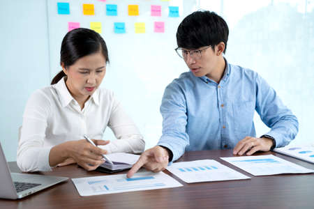 Businessmen and woman are standing He giving advice and brainstorming for Find an ideal and Write to notepad and stick it on the board.の写真素材
