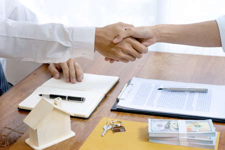 Sale representative or insurance broker handshake with customer after house purchase contract buy a house or apartmentの写真素材