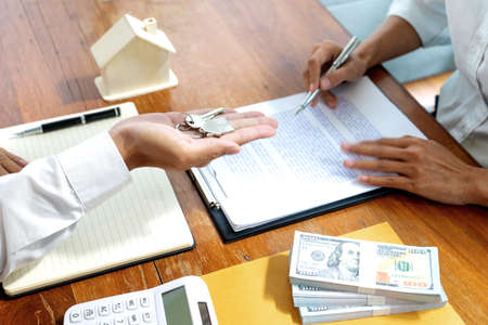 Sale representative or insurance broker offer house purchase contract to buy a house or apartment and give home key chain to customerの写真素材