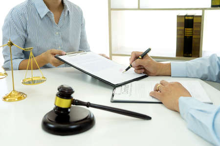 The businesswoman sit and look examined the documents the standing staff presented while working in the office.の写真素材