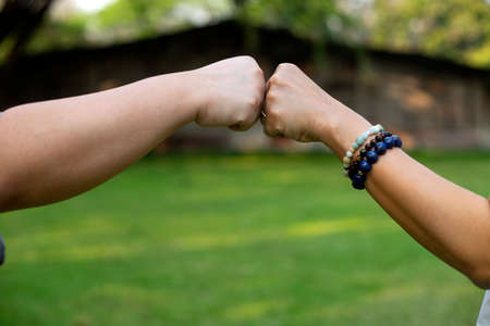 Close up image of two hand fist bump at the outdoor area green background to show their feeling...