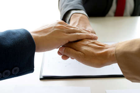 Businessmen stack their hands to show cooperation after a business deal meeting team partnership or...