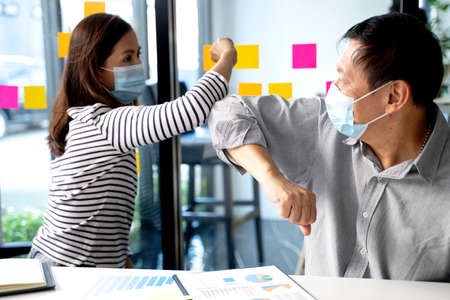 Businessman  wearing a mask  say hi to another no handshake but use elbow bump in the concept new normal.の写真素材