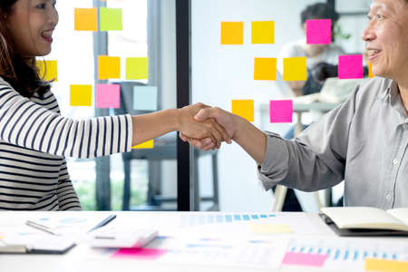 Two smile business people are shaking hands to congratulate them on a successful business deal.