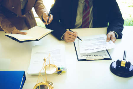 The lawyer and assistant are helping to review and will sign the document on the table had gavel and balance in law firm sepia vintage tone.の写真素材