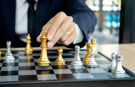 A business man in a suit is holding a chess king figure on the board concept chess strategy  conceptの写真素材
