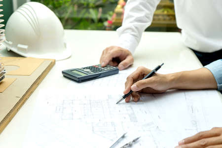 Engineers and architects are discussing and revising plans for building construction projects on floor plans and building models.の写真素材