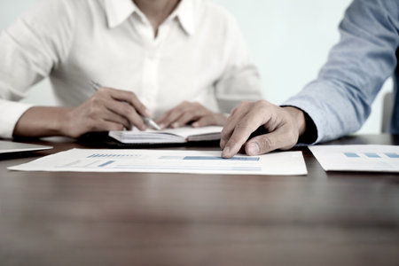 The businessman pointed to the company's marketing material  where the staff was writing information in a notebook retro tone with more copy spaceの写真素材