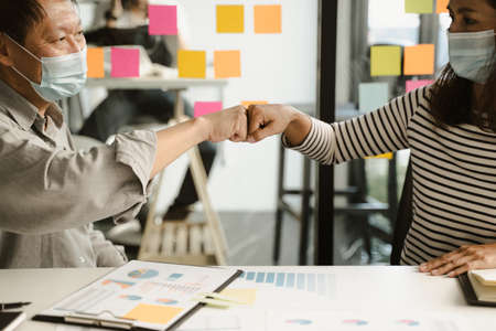 two business people use hand to fist bump in succes Partner Business Teamwork wearing  mask not to risk COVID-19 the new coronavirus in the concept new normal vintage tone.の写真素材