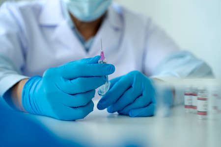 Scientists or doctor are preparing a covid-19 vaccine with syringe for the public to prevent infection bottle with the vaccine for coronavirus cure in the labÂ の写真素材