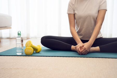 Young woman stretching on a yoga mat to relax or prepare to exercise have  a dumbbell and a water bottle.の写真素材