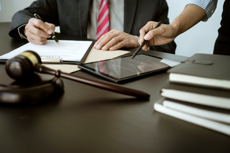 The lawyer is write drafting a legal document while listening to the assistant use her tablet to...