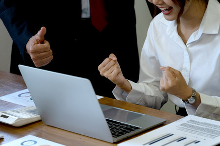 Young asian businesswoman Sit showing joyful expressions of hope in front of a laptop with a manager or boss standing nearby.の写真素材