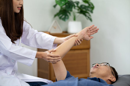 Asian young woman physiotherapist doing postures arm to cure and alleviate elderly patient's illness.の写真素材