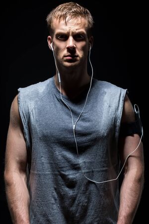 Fitness man in grey sleeveless shirt is sweating and lookingの写真素材