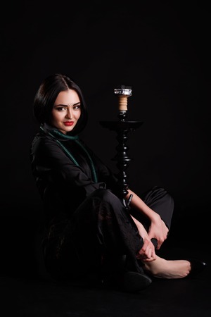 Young attractive girl in elegant dress and hookah in studio.