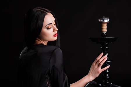 Young attractive girl in elegant dress and hookah in studio.の写真素材