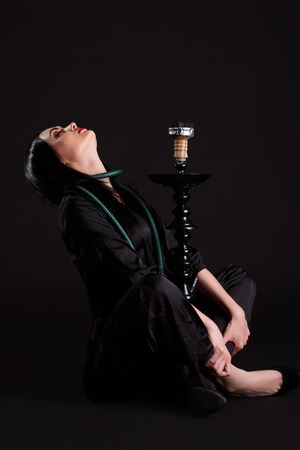 Beauty portrait of young curly brunette woman enjoying the hookah.の写真素材