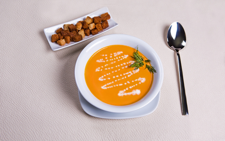 A plate of pumpkin cream soup with croutons and dill.の写真素材