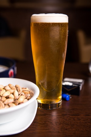 Glass of beer and peanut on the wooden background.の写真素材