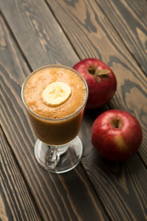 Fruit smoothie in a glass and apples on wood.の写真素材