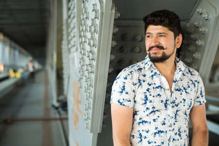 Portret of stylish bearded brunette guy. Young man posing on camera, dressed in light printed shirtの写真素材