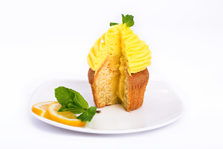 Lemon yellow cut cupcake with mint on a white background.の写真素材
